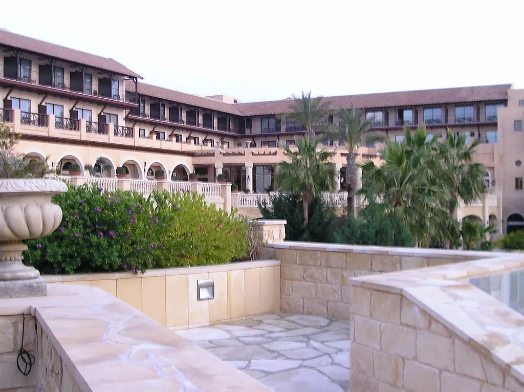 Hotelgebouw met balkons en palmbomen rond een stenen terras bij het zwembad in Paphos