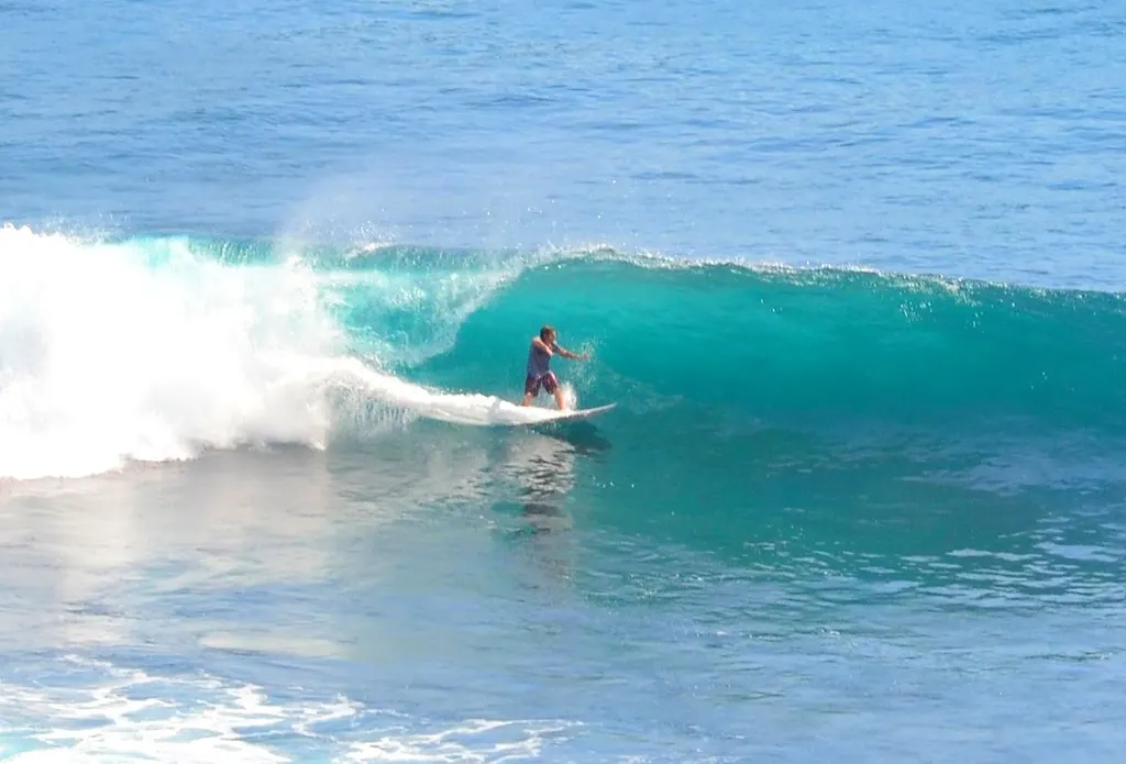 Surfer rijdt op een turquoise golf in de oceaan bij Uluwatu op Bali