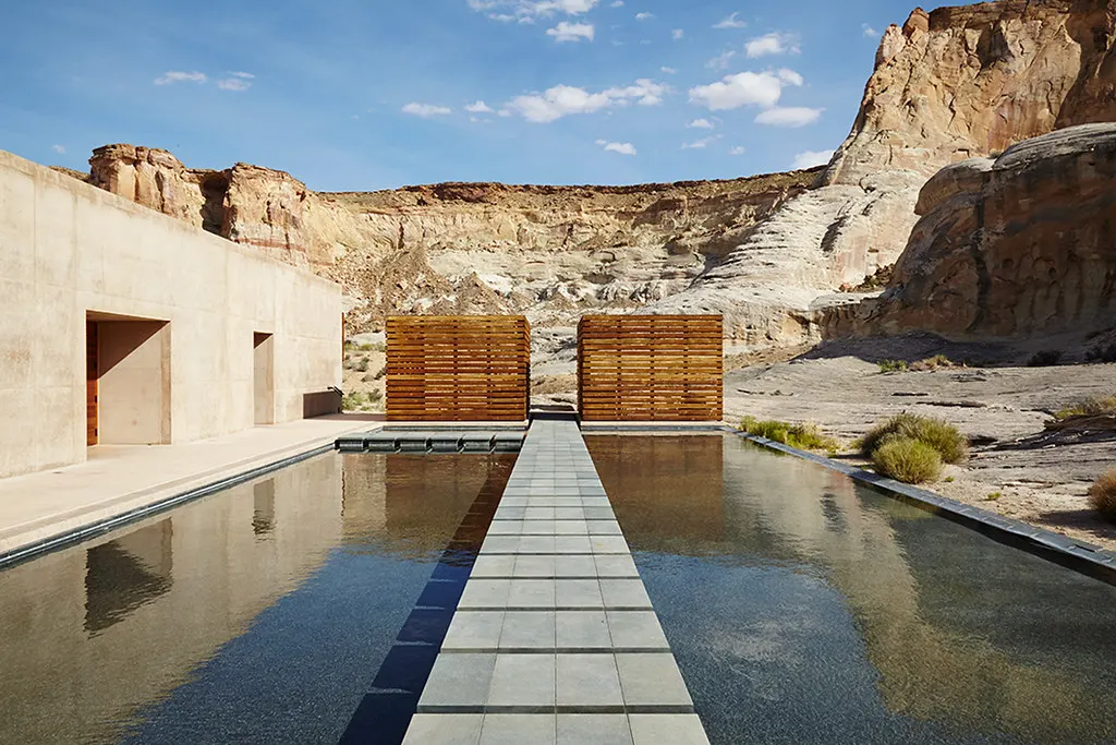 Zwembad van Amangiri met stenen looppad tussen betonnen gebouwen en rotswanden in de woestijn van Utah