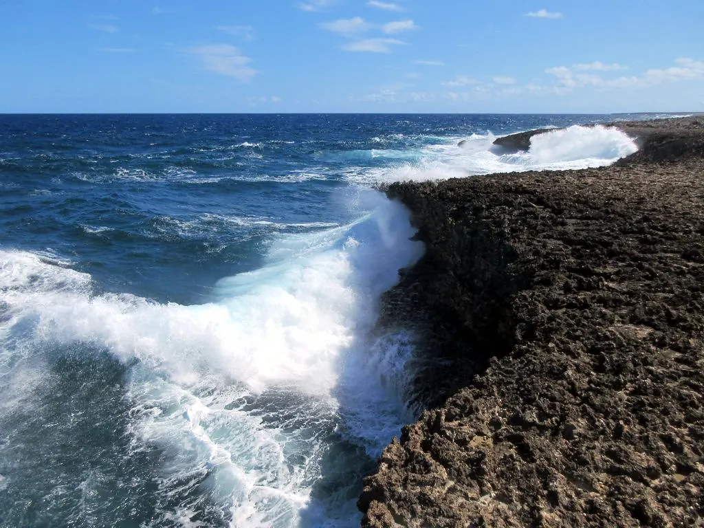 Woeste golven slaan tegen de ruwe kalkstenen kliffen van Shete Boka op Curaçao