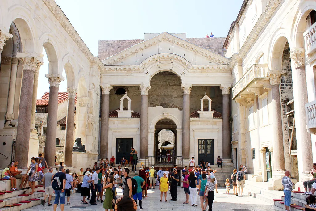 Het zonnige Peristilplein in Split met Romeinse zuilen en arcades, de vestibule en toeristen op het plein