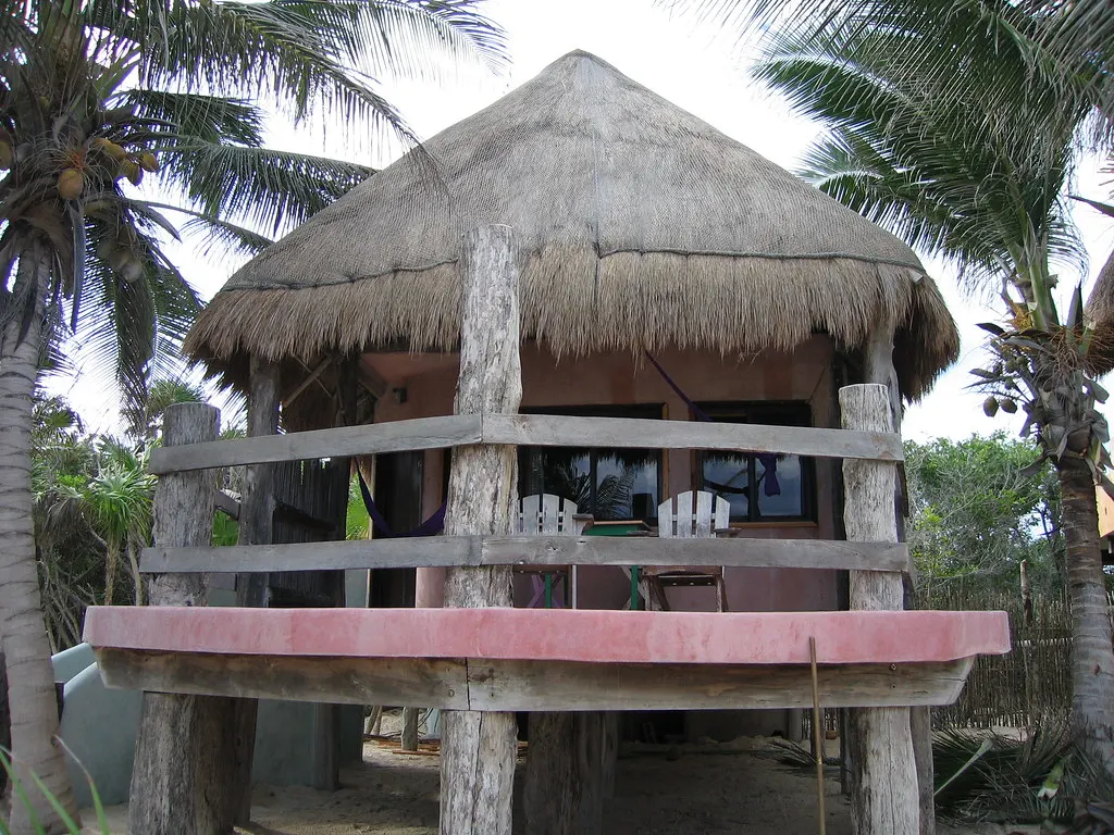Strandcabana met rieten dak en houten veranda tussen palmbomen bij Zamas Hotel in Tulum
