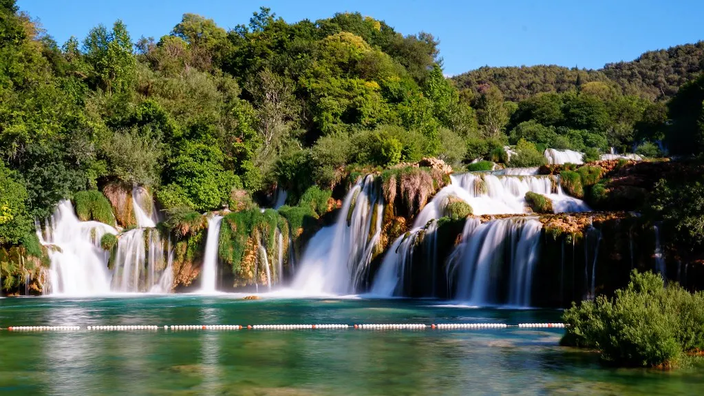 Brede waterval Skradinski Buk met meerdere cascades tussen groene bomen en turquoise water in Nationaal Park Krka