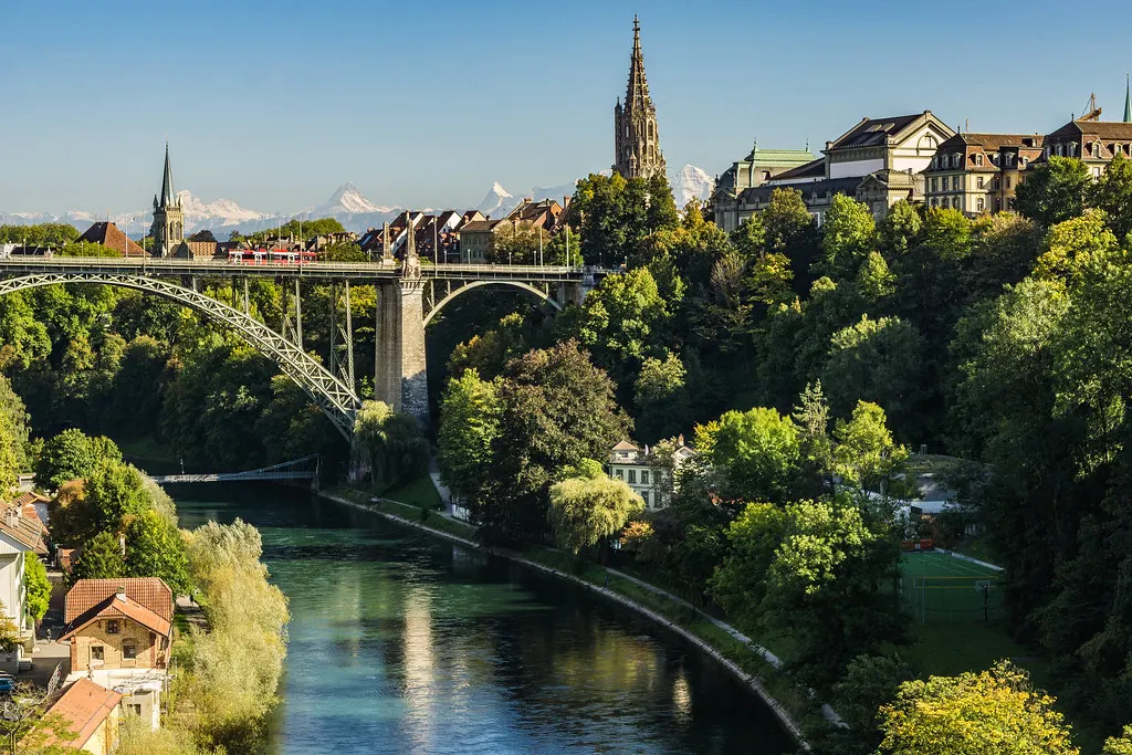 Uitzicht over de Aare in Bern met de Kirchenfeldbrug, de Berner Münster en besneeuwde Alpen op de achtergrond