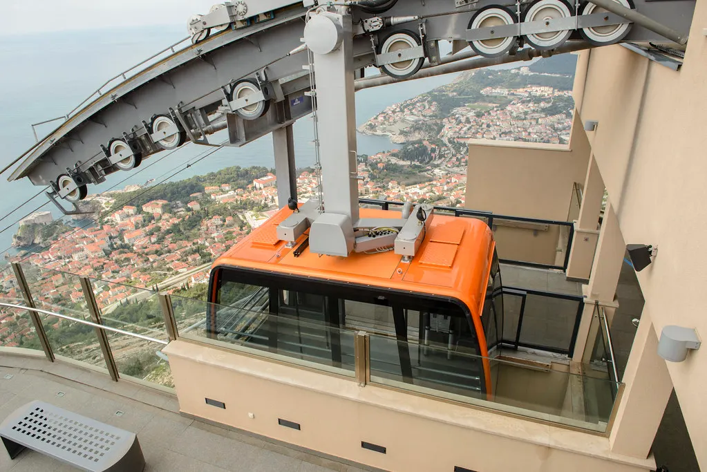 Oranje cabine van de kabelbaan in het bergstation op de Srđ, met uitzicht op Dubrovnik en de zee