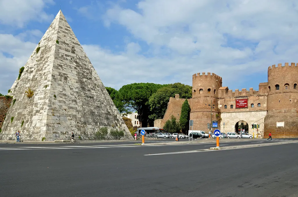 De witte Piramide van Cestius naast de middeleeuwse Porta San Paolo in Rome onder een blauwe lucht