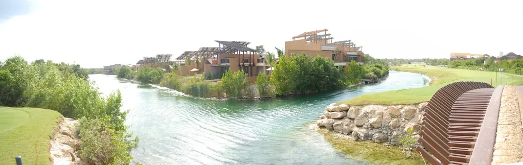 Villa's van het Mayakoba-resort langs een turquoise lagune omringd door groen en golfbaan