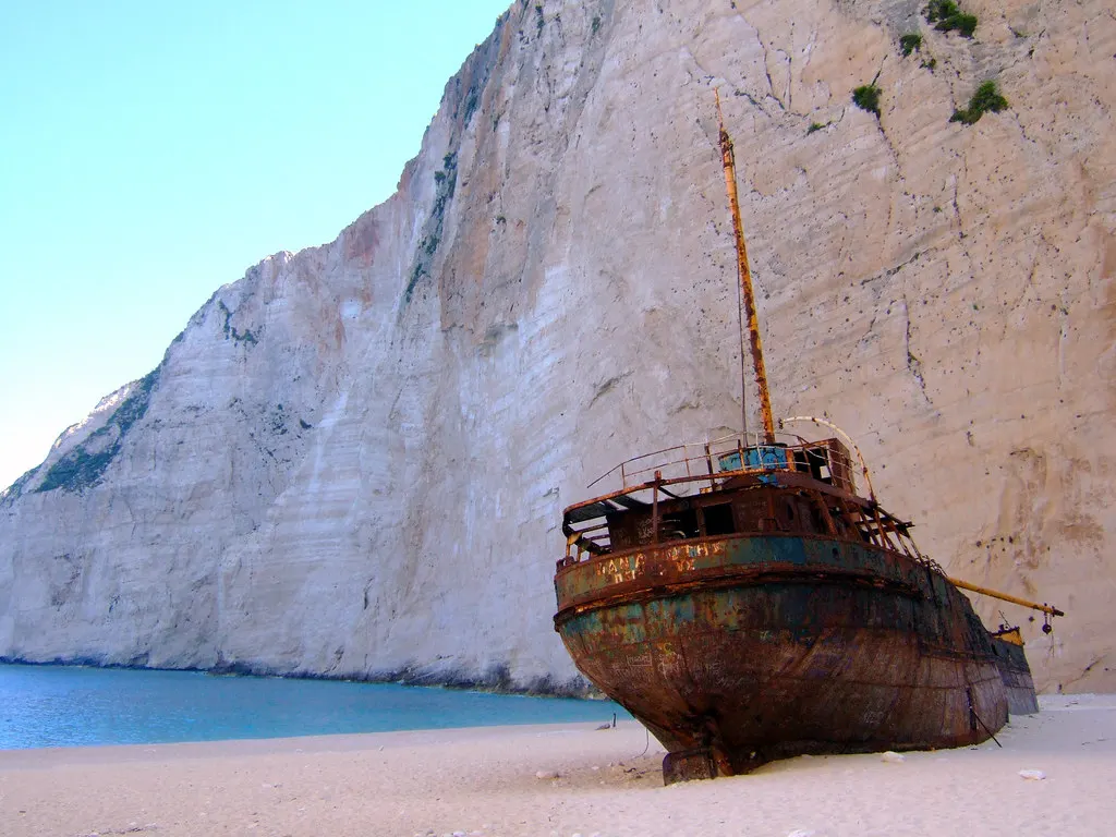 Roestig scheepswrak op het witte zandstrand van Navagio Beach, met een steile kalkstenen rotswand erachter