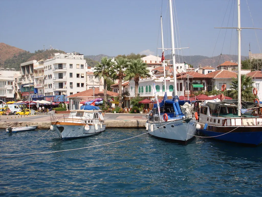 Zeilboten afgemeerd aan de kade van Marmaris met palmbomen, terrasjes en witte gebouwen op de achtergrond