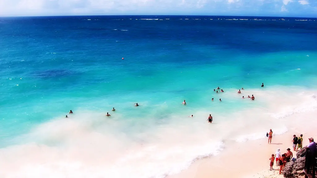Turquoise Caribische Zee met zwemmers en een wit zandstrand, gezien vanaf een hoge kust