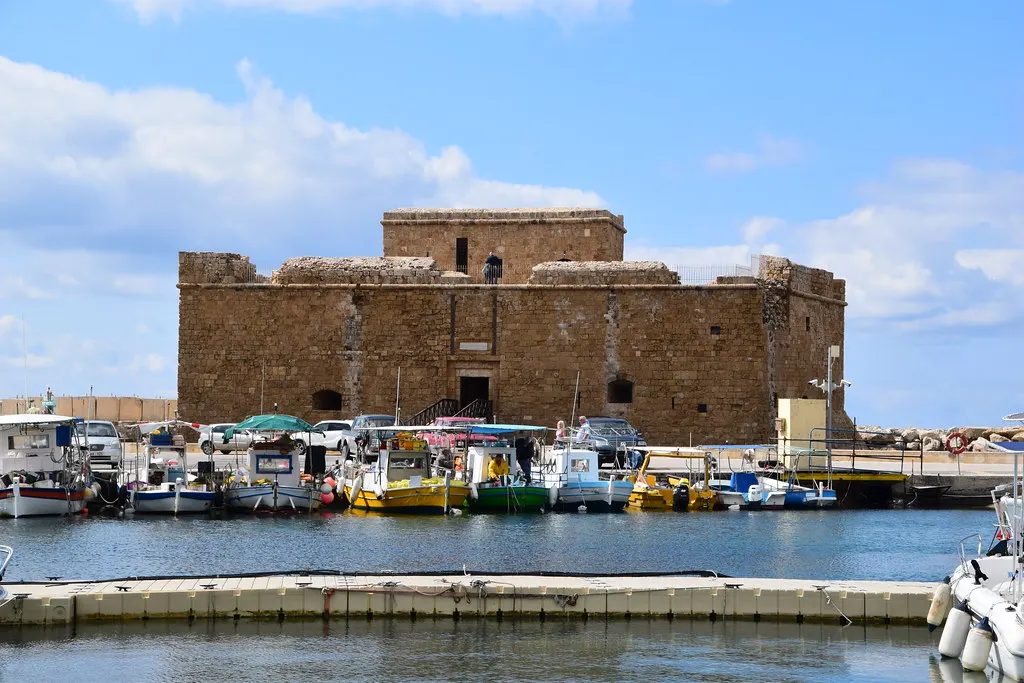 Middeleeuws fort van Paphos achter de haven met kleurrijke vissersboten onder een blauwe lucht