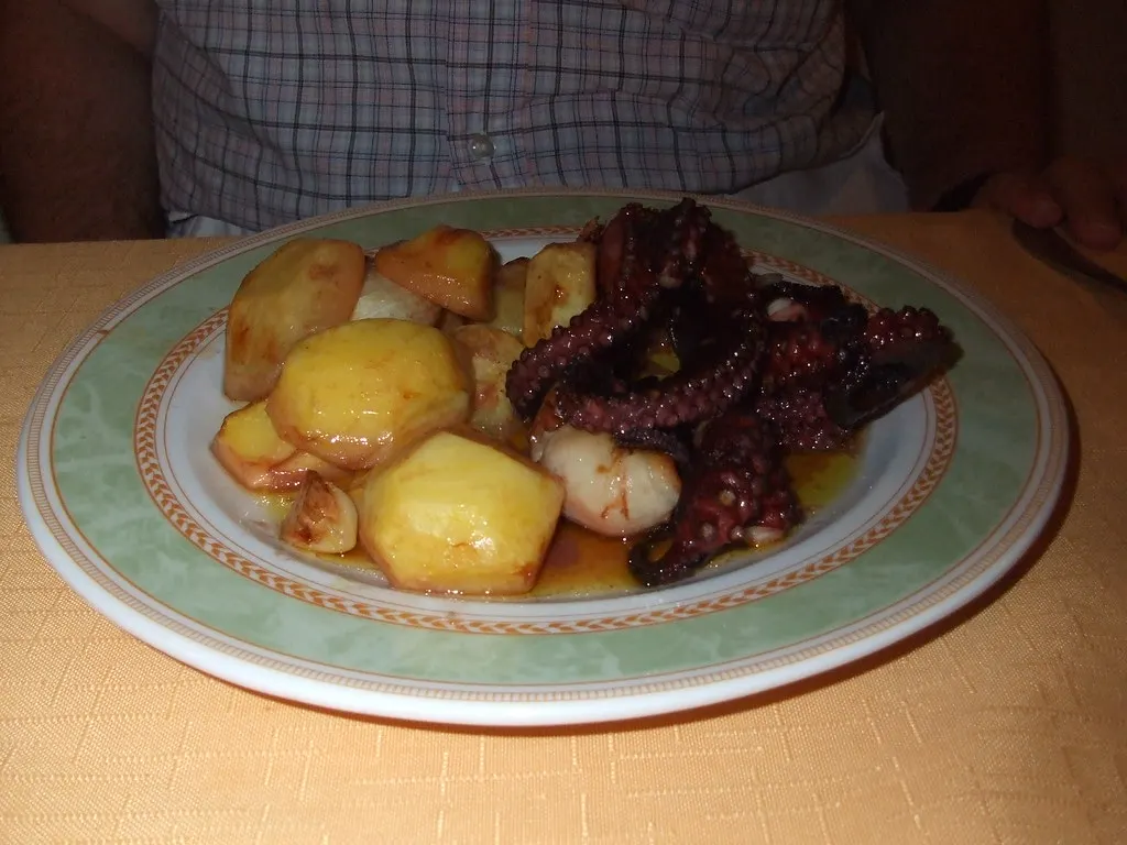 Bord met gegrilde octopus en gebakken aardappelen op een restauranttafel