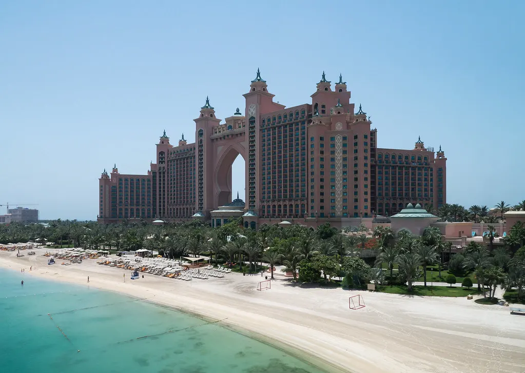 Het roze Atlantis The Palm hotel met zijn karakteristieke boog achter een wit zandstrand en turquoise zee