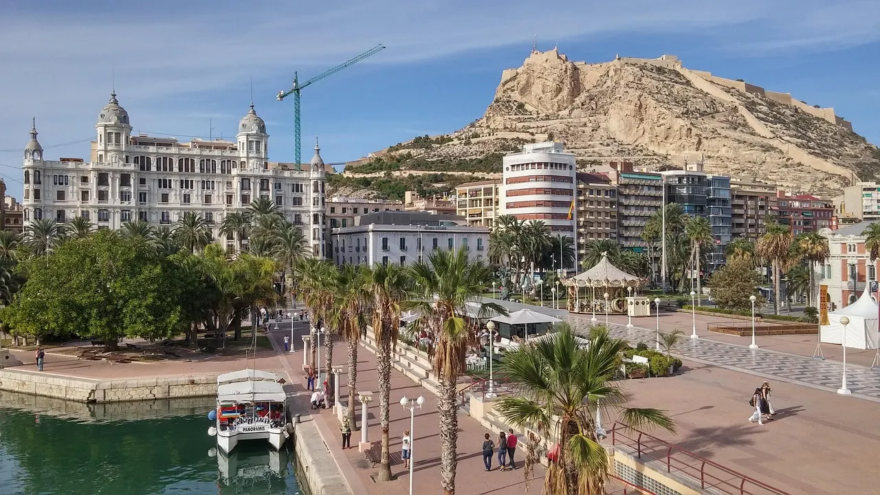 Haven van Alicante met palmen en boulevard, op de achtergrond de berg met kasteel Santa Bárbara