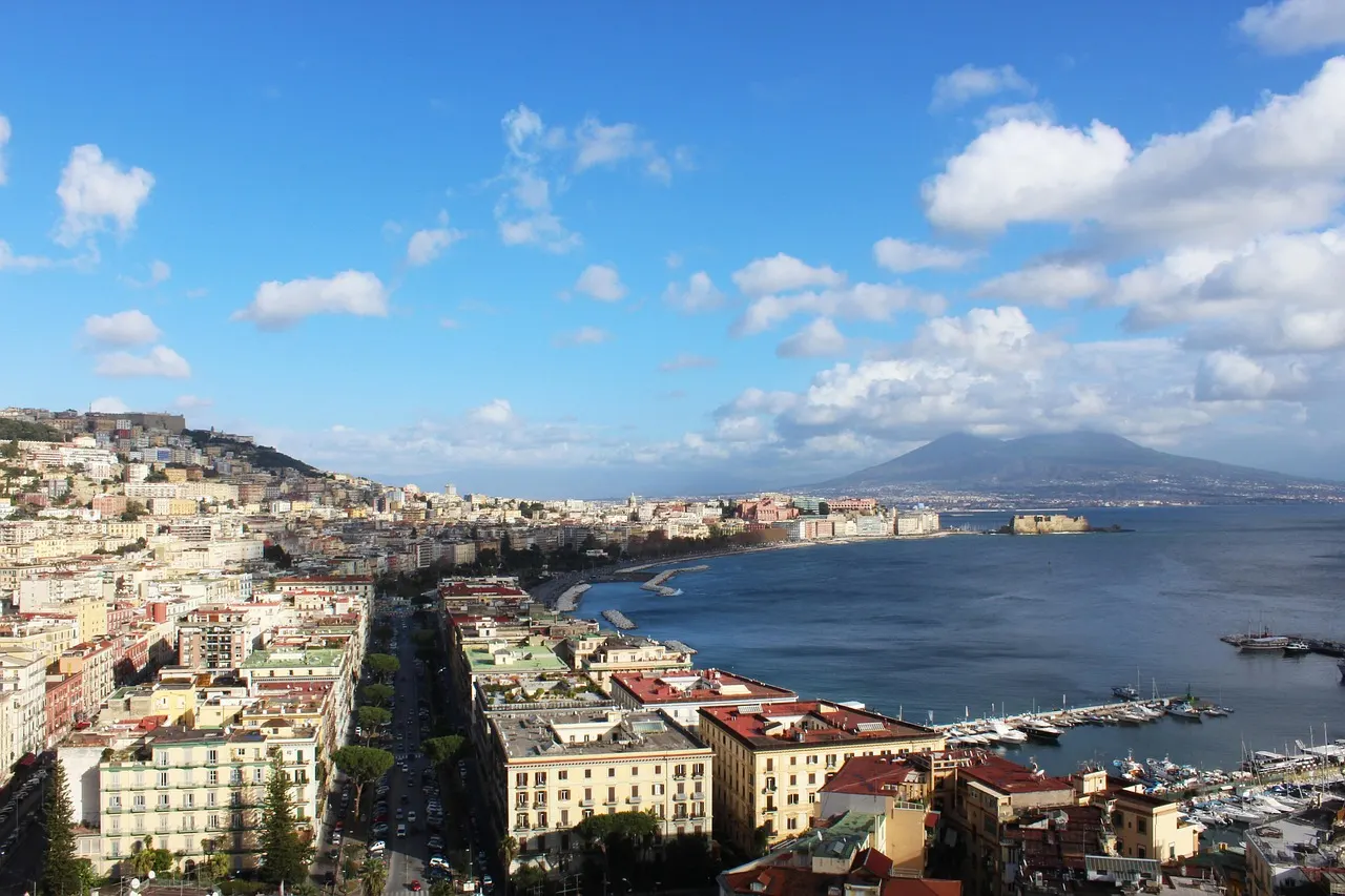 Uitzicht over Napels met de haven, de Golf van Napels, Castel dell'Ovo en de Vesuvius onder een blauwe lucht