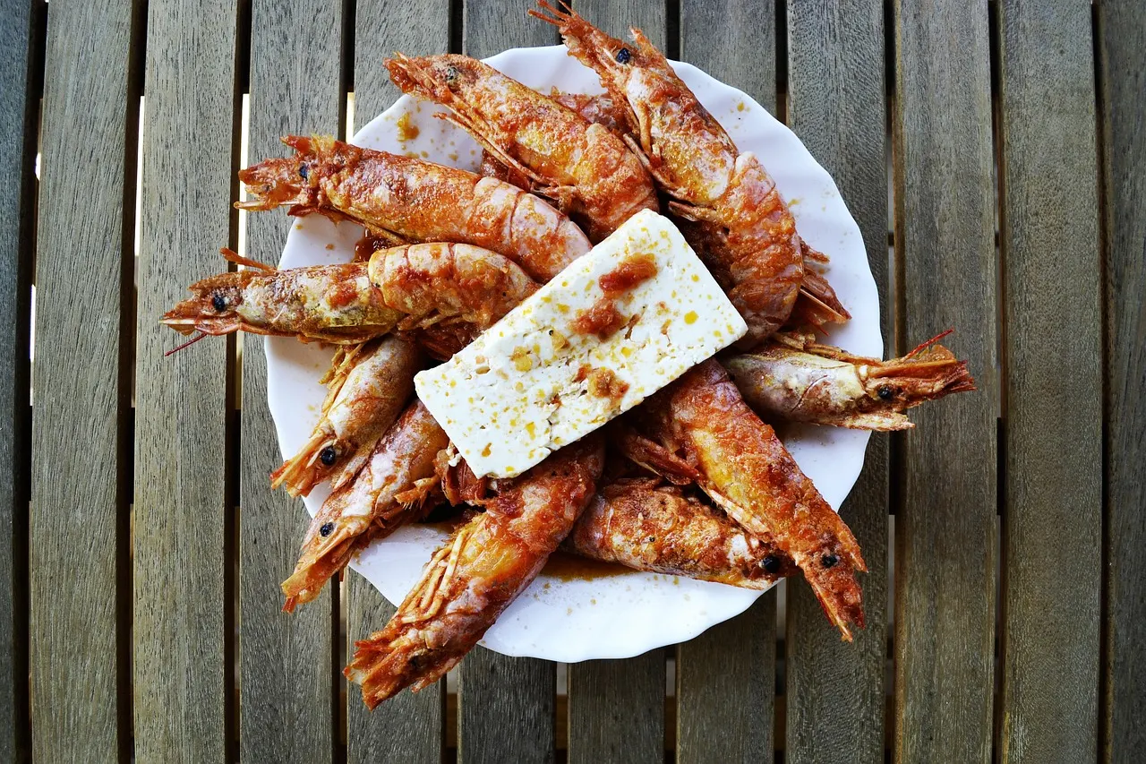 Bord met gegrilde garnalen en een plak feta op een houten tafel