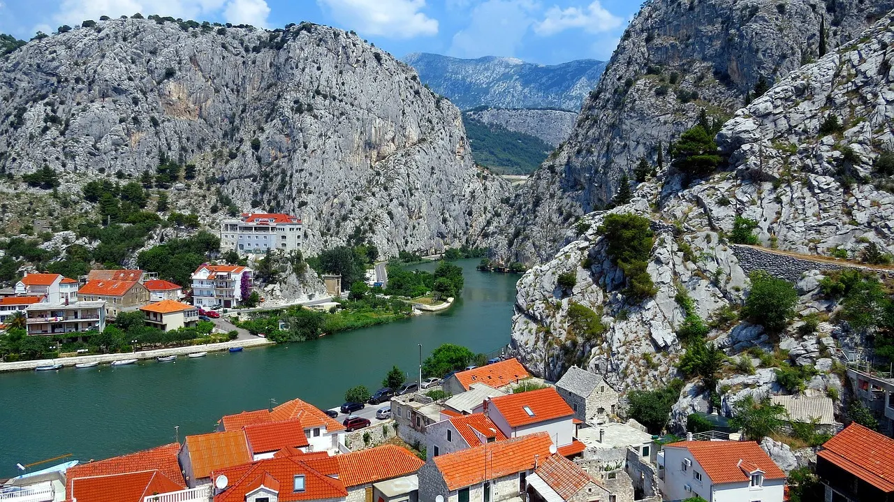 Omiš met oranje daken aan de groene Cetina-rivier, ingeklemd tussen steile grijze kalksteenrotsen