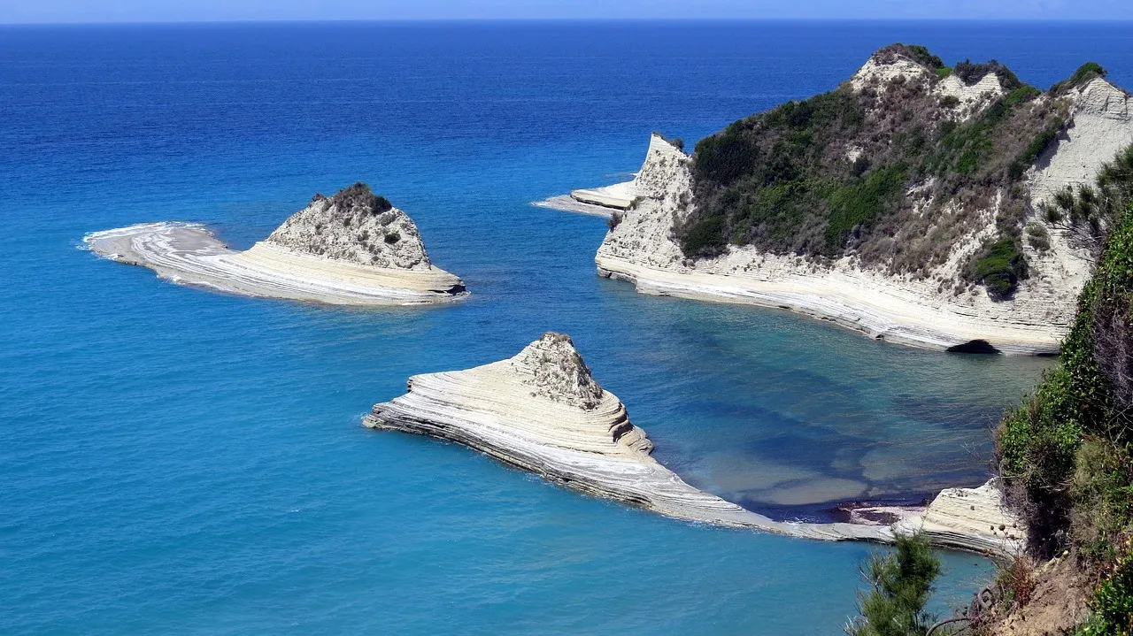 Witte kliffen en rotspunten van Kaap Drastis in een helderblauwe zee aan de noordkust van Corfu