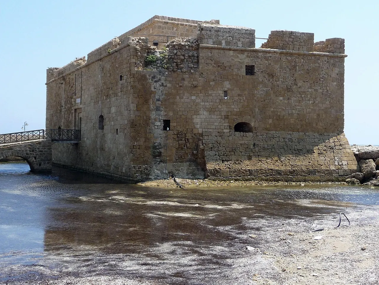 Middeleeuws stenen fort van Paphos aan het water met een kleine brug, onder een blauwe lucht
