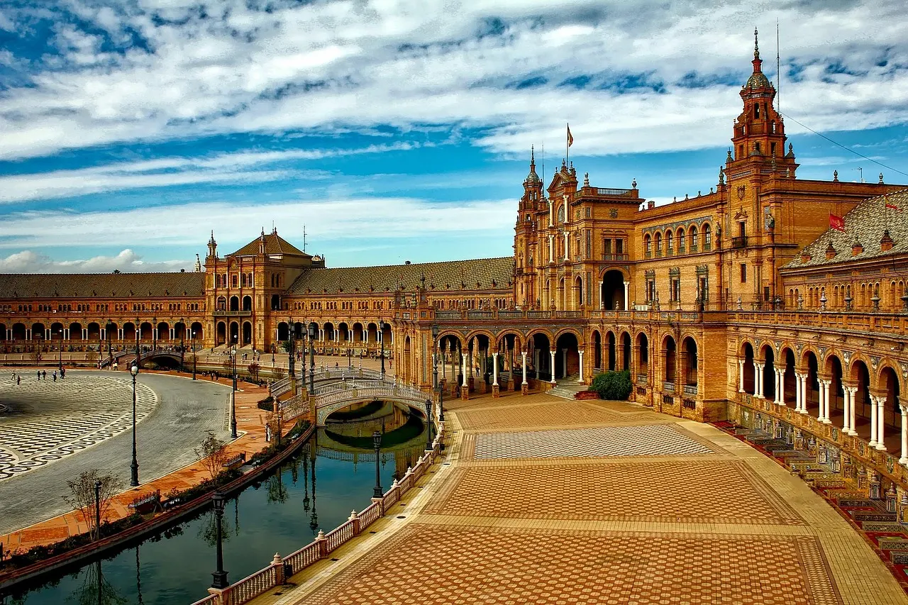 Plaza de España in Sevilla met gracht, sierlijke brug en het halfronde paleis onder een blauwe lucht