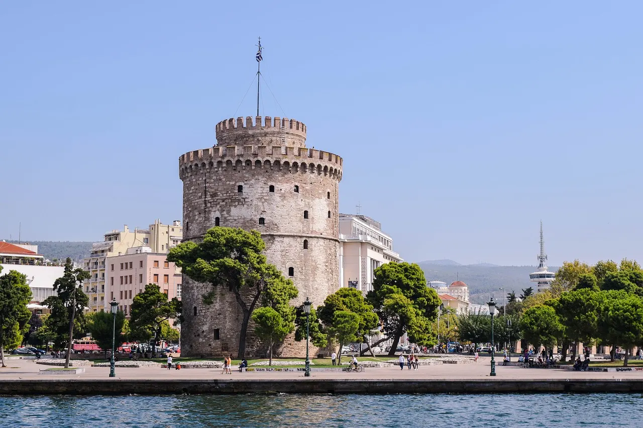 De Witte Toren van Thessaloniki aan de boulevard, gezien vanaf het water onder een heldere blauwe lucht