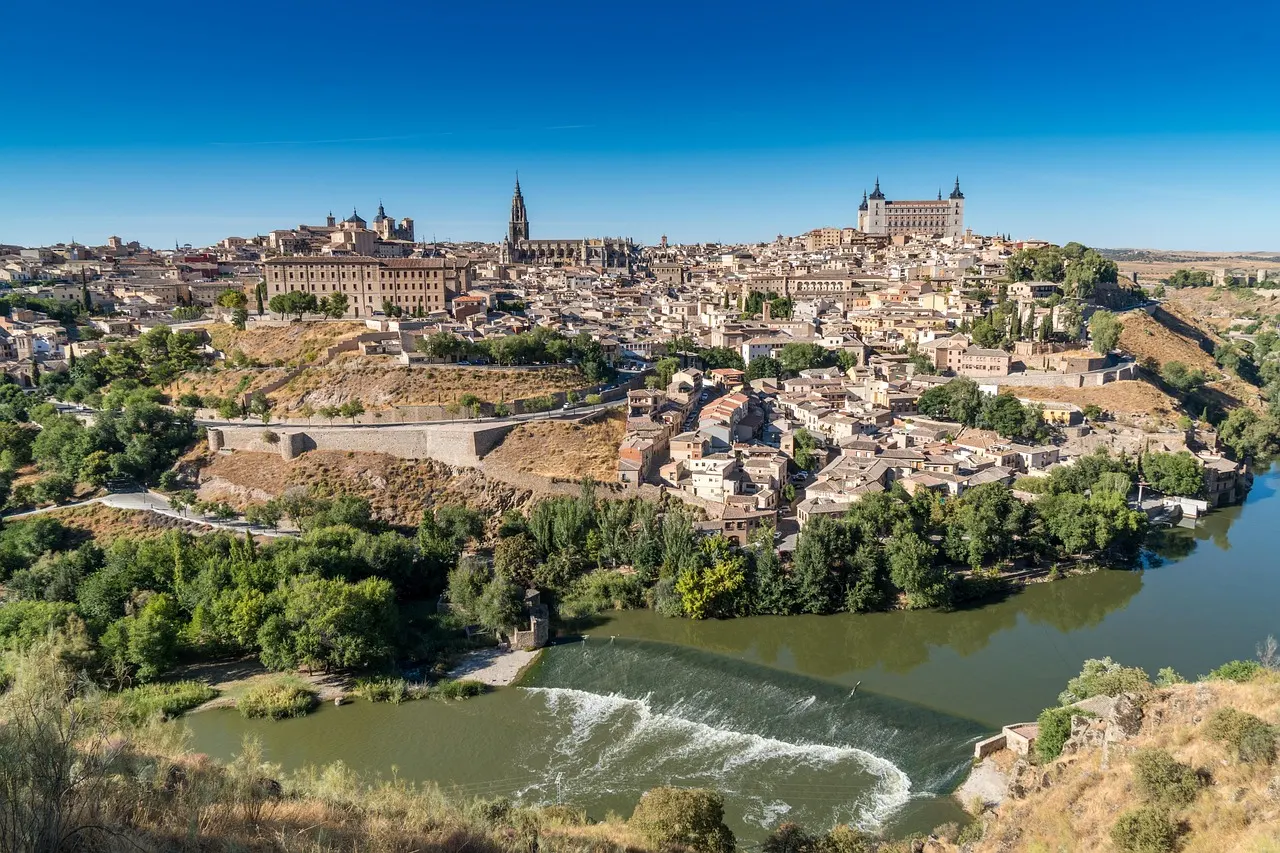 Skyline van Toledo met de kathedraal en het Alcázar boven de rivier de Taag onder een strakblauwe lucht