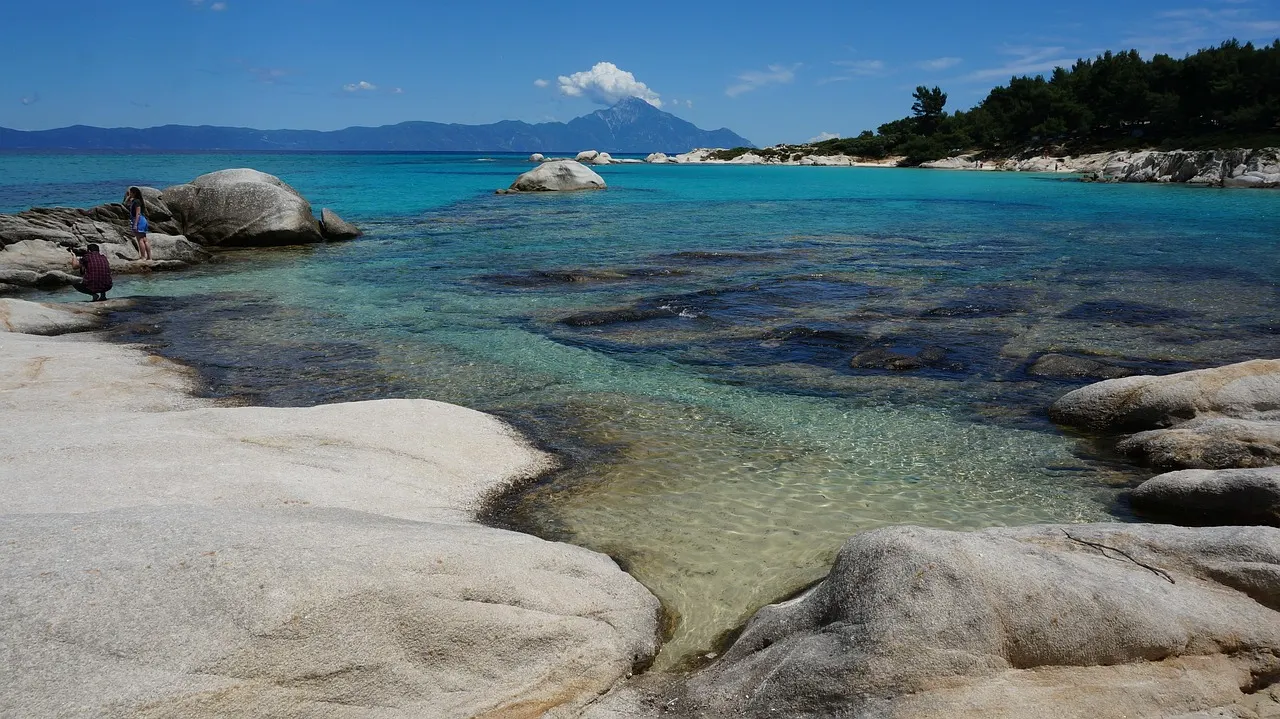 Turquoise baai met witte granietrotsen op Sithonia, Chalkidiki, met de berg Athos aan de horizon