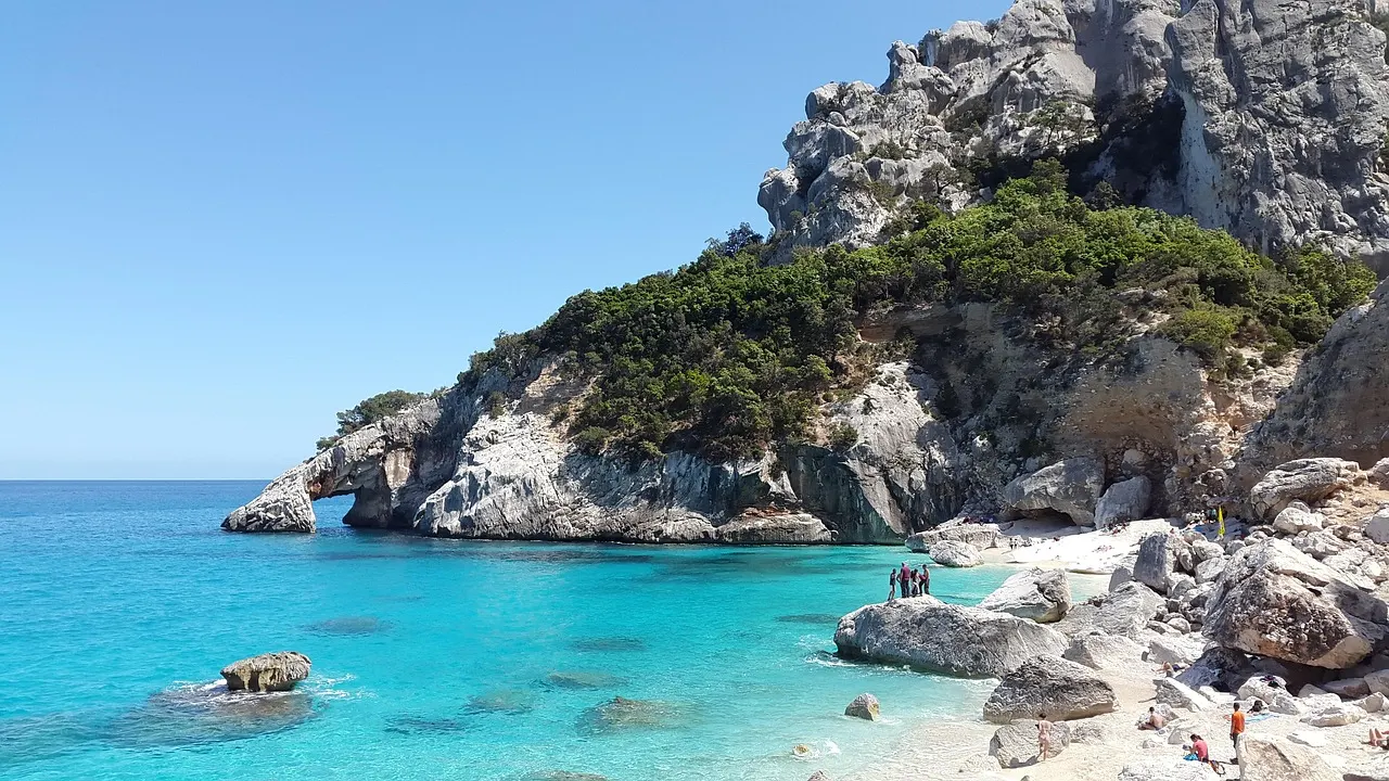 Turquoise baai met witte kalkrotsen en groene begroeiing aan de kust van Sardinië
