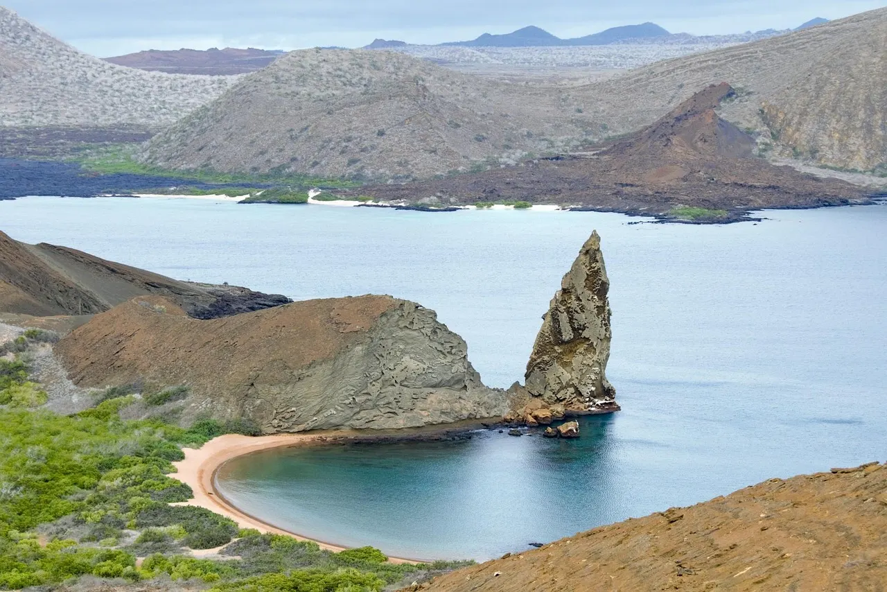 Pinnacle Rock en een halvemaanvormig strand bij Bartolomé, met vulkanische eilanden en blauwe zee