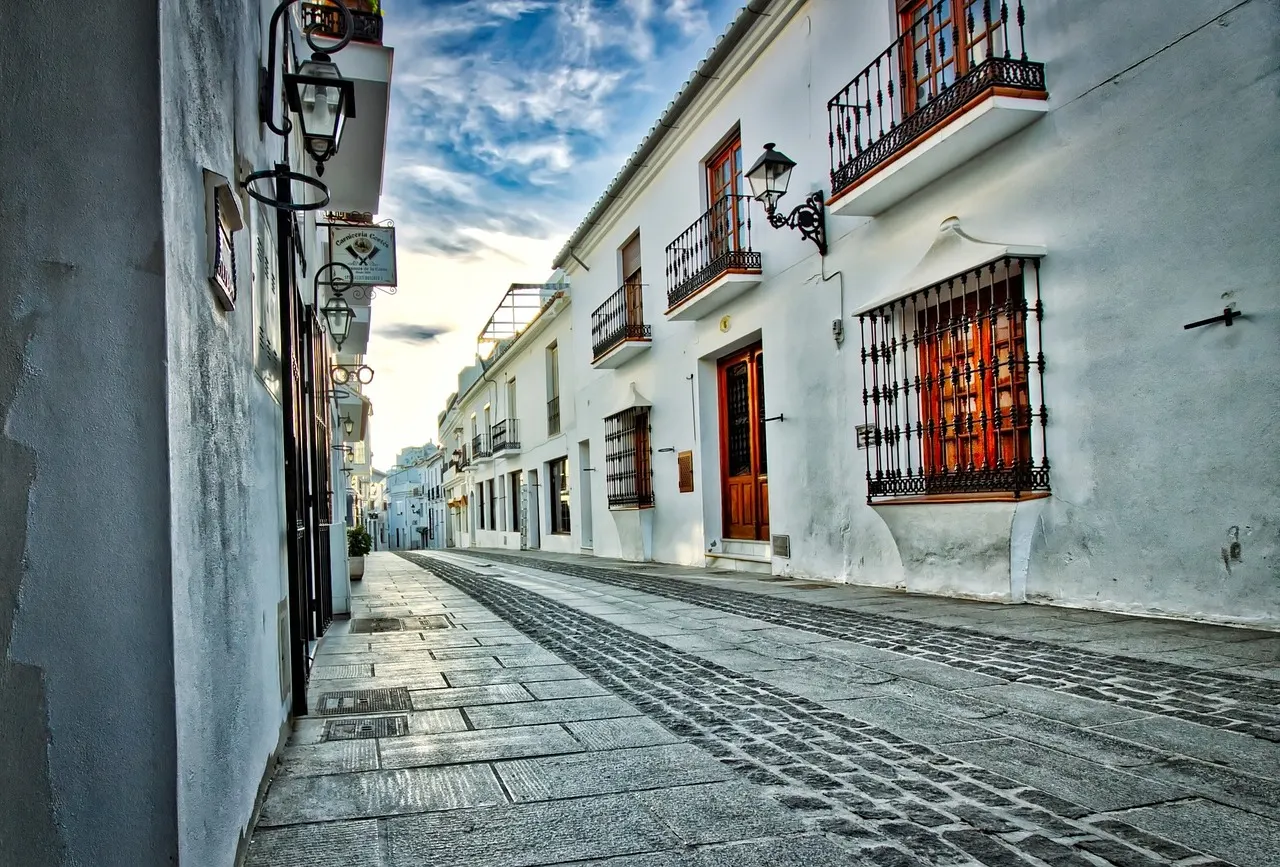 Witte straat met smeedijzeren balkons, lantaarns en kinderkopjes in het dorp Mijas Pueblo