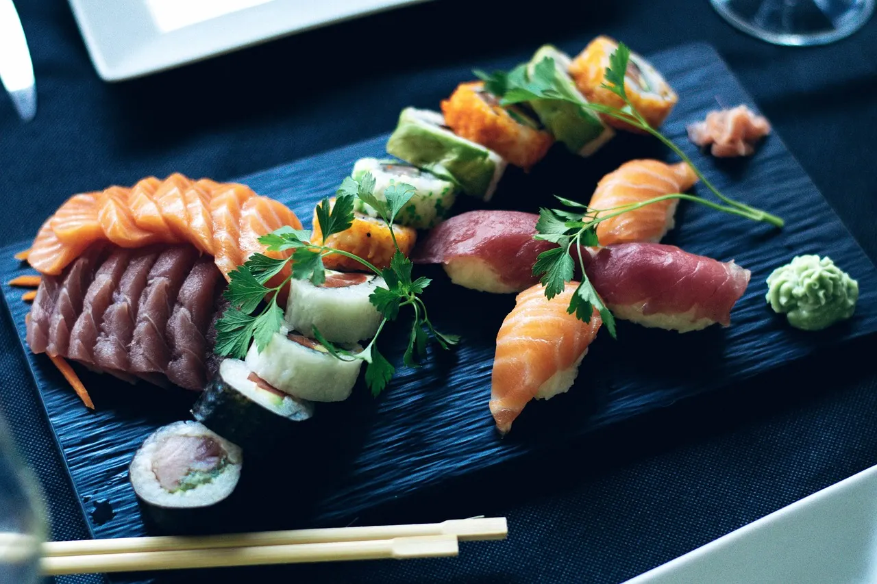 Sushiplank met sashimi van zalm, nigiri en maki, gegarneerd met peterselie, gember en wasabi