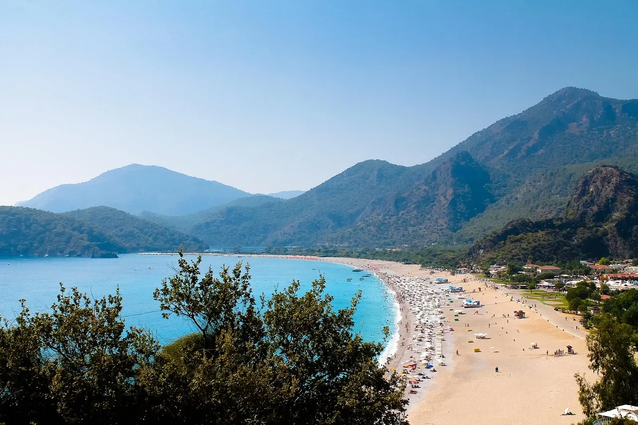 Turquoise baai met lang zandstrand en beboste bergen bij Ölüdeniz aan de Turkse kust