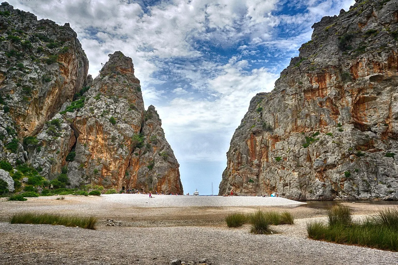 Kiezelstrand van Sa Calobra tussen hoge rotswanden van de Torrent de Pareis-kloof onder een bewolkte lucht