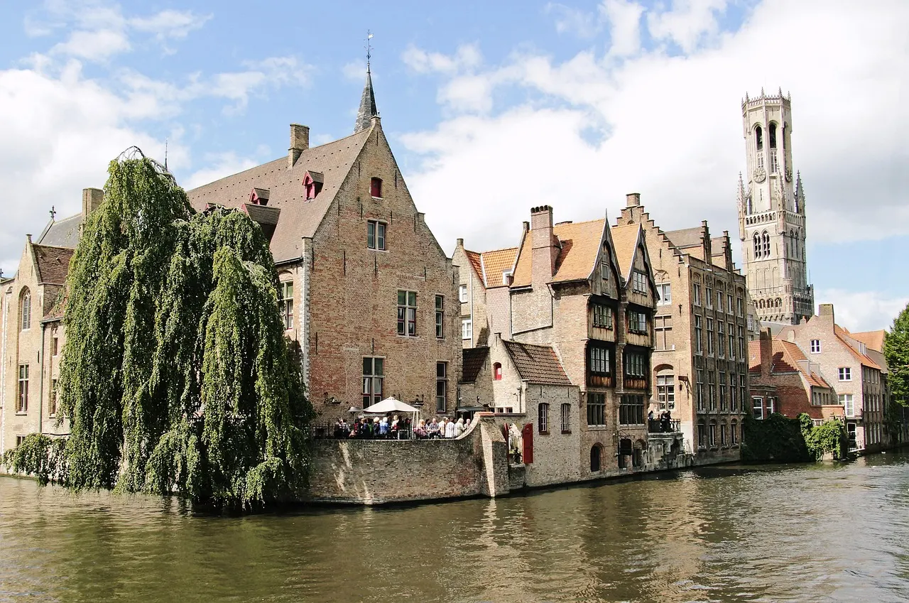 Rozenhoedkaai in Brugge met middeleeuwse huizen aan de gracht, treurwilg en het Belfort op de achtergrond