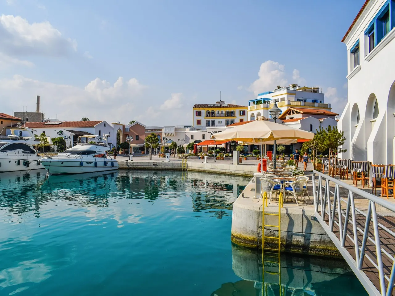 Jachthaven van Limassol met boten, turquoise water, terrasjes en witte gebouwen onder een blauwe lucht