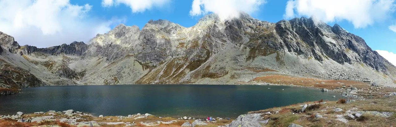 Bergmeer omringd door rotsachtige toppen van de Hoge Tatra onder een blauwe lucht met wolken