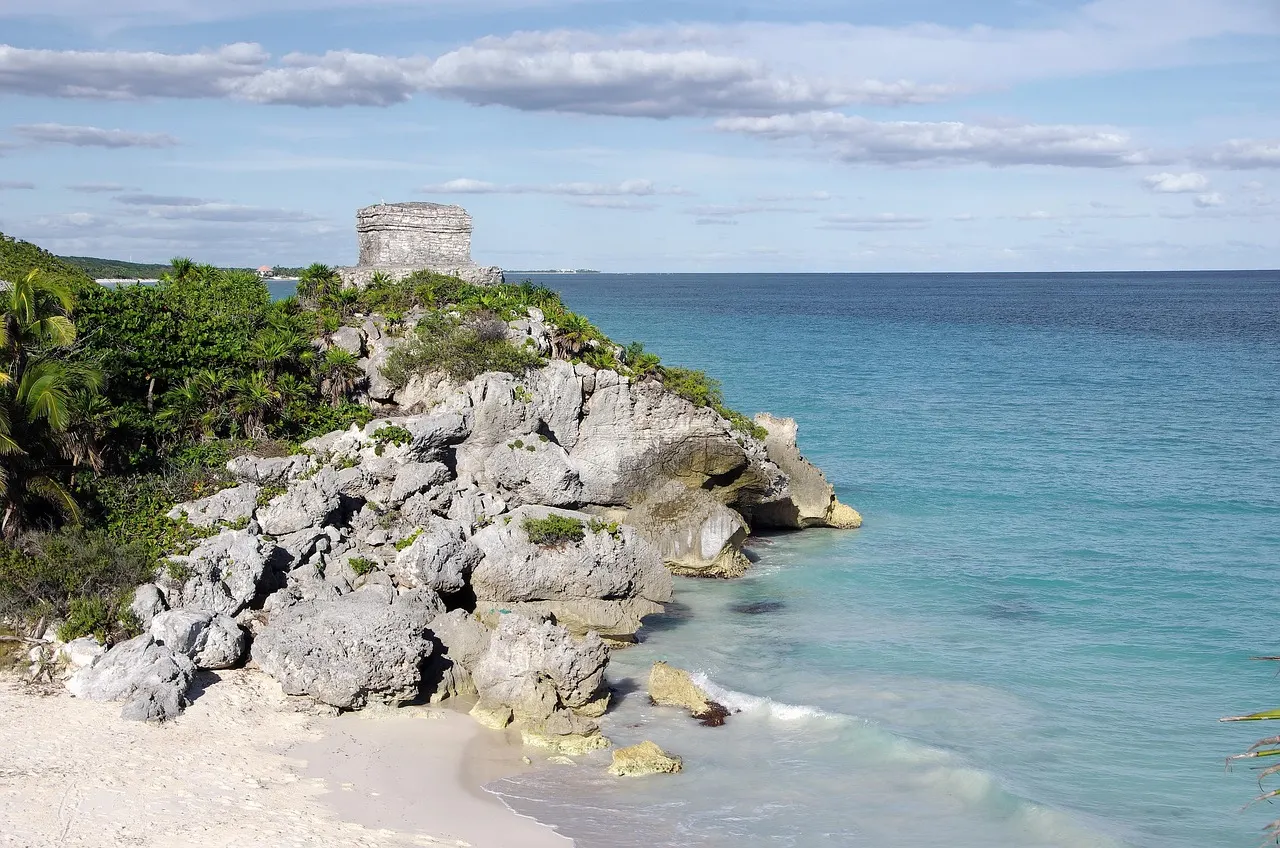 Rotsachtige kust van Tulum met turquoise zee, wit zandstrand en een Mayaruïne op de klif