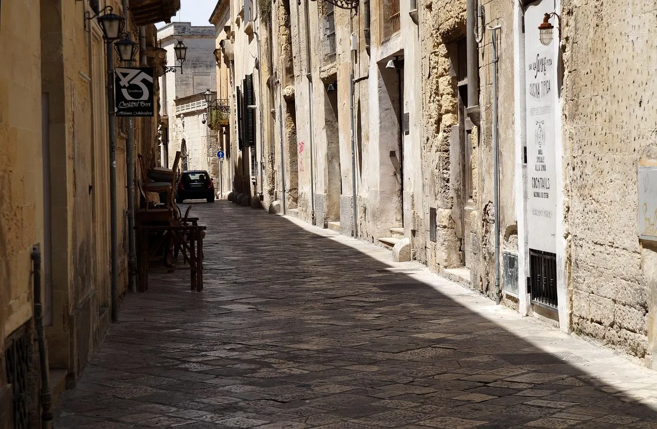 Smal straatje met lichte kalkstenen gevels, lantaarns en plaveisel in het historische centrum van Lecce