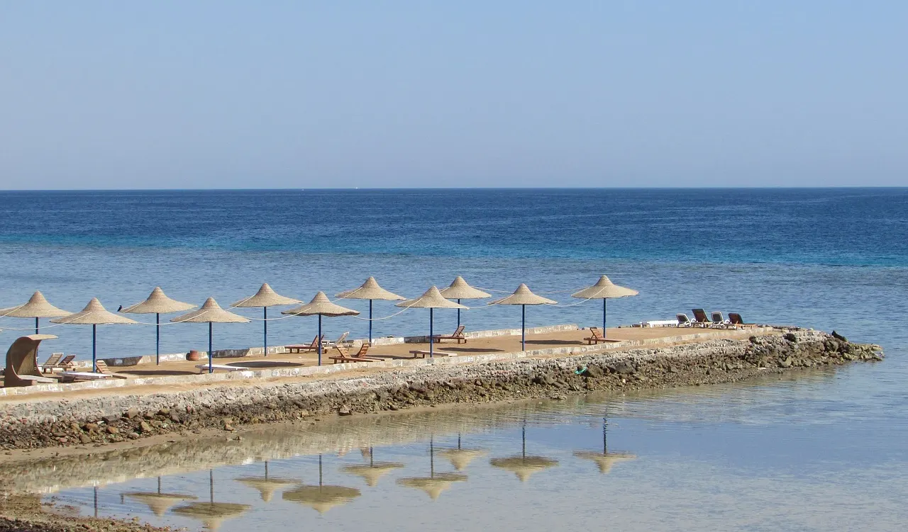 Strand met rieten parasols op een pier aan de blauwe Rode Zee bij Hurghada