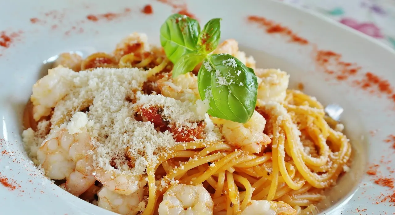 Bord spaghetti met garnalen, tomatensaus, geraspte kaas en verse basilicum