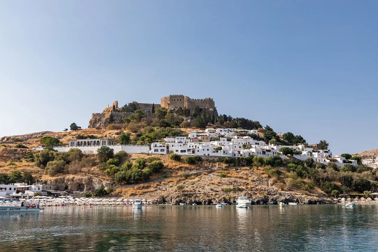 Lindos met de akropolis op de heuvel en witte huisjes boven de baai met boten