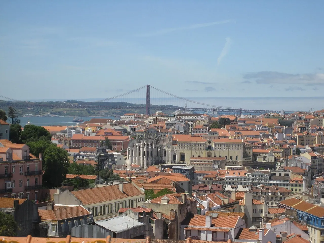 Uitzicht over de rode daken van Lissabon met de Carmo-kerk, de Taag en de brug 25 de Abril
