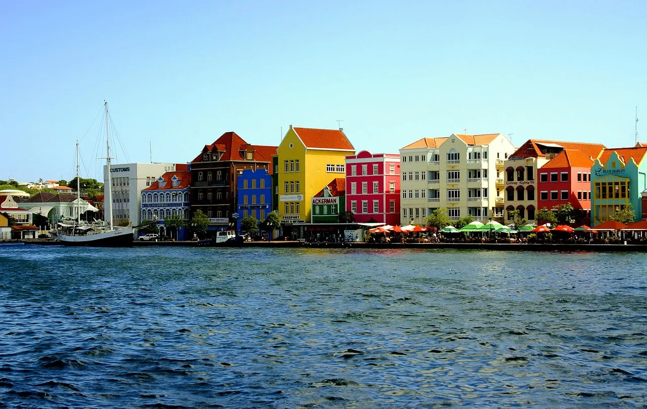 Kleurrijke koloniale gevels aan de Handelskade in Willemstad, gezien over het water van de Sint Annabaai