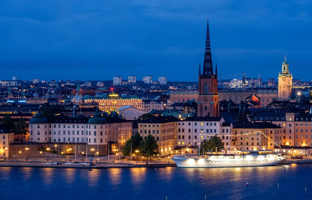 Avondpanorama van Riddarholmen en Gamla Stan in Stockholm met verlichte kerktorens en een boot op het water