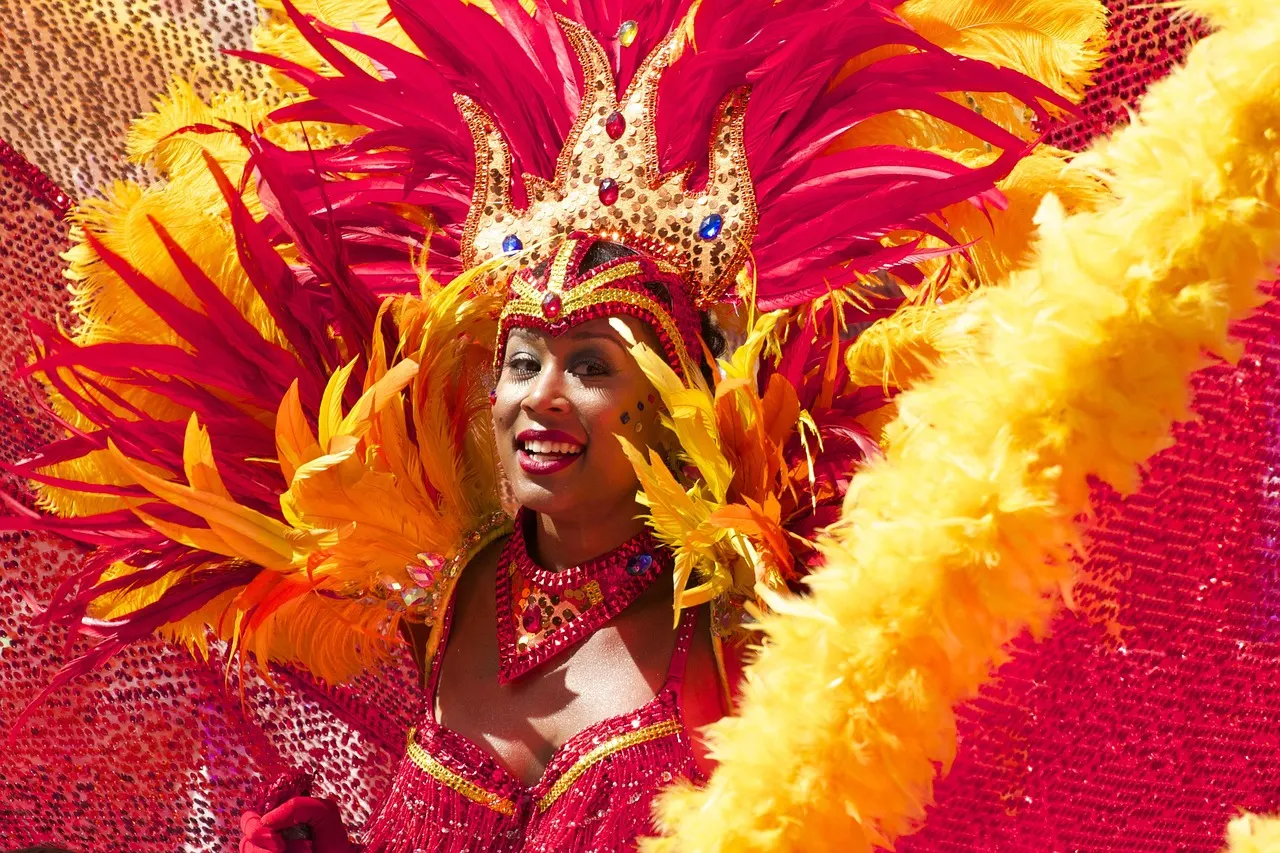 Lachende carnavalsdanseres in kostuum met rood-gele veren en kroon tijdens een parade