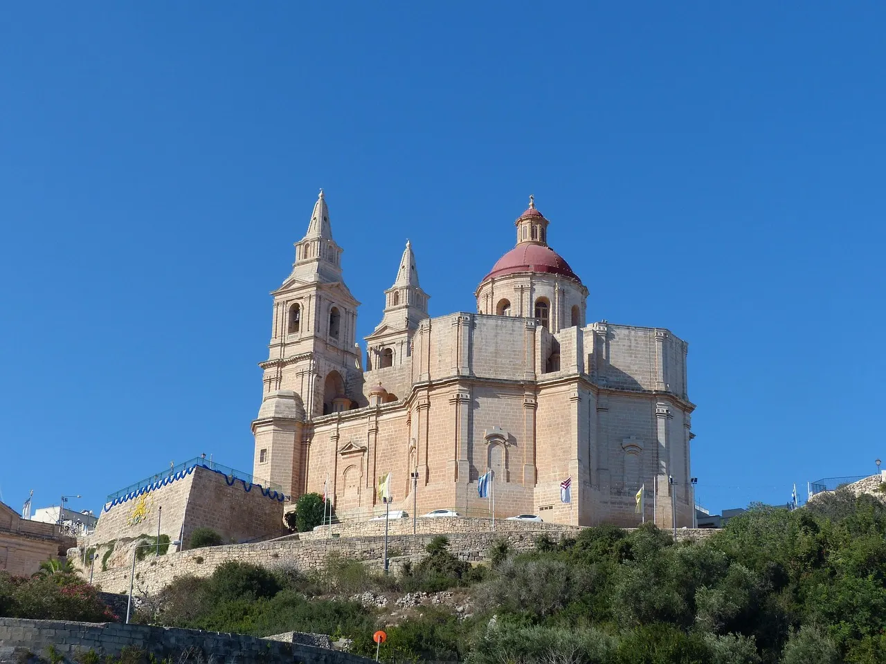 De parochiekerk van Mellieħa met koepel en twee torens op een heuvel onder een strakblauwe lucht