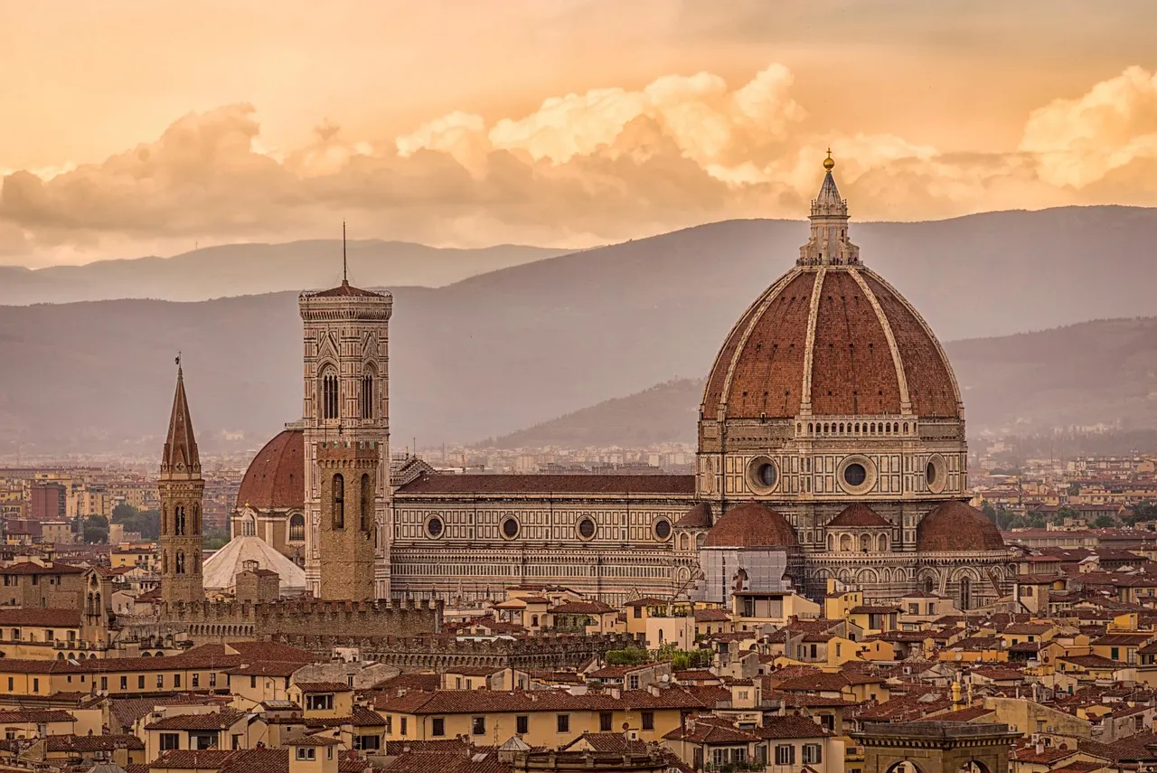De Dom van Florence met koepel en klokkentoren boven de daken van de stad, met heuvels in warm avondlicht