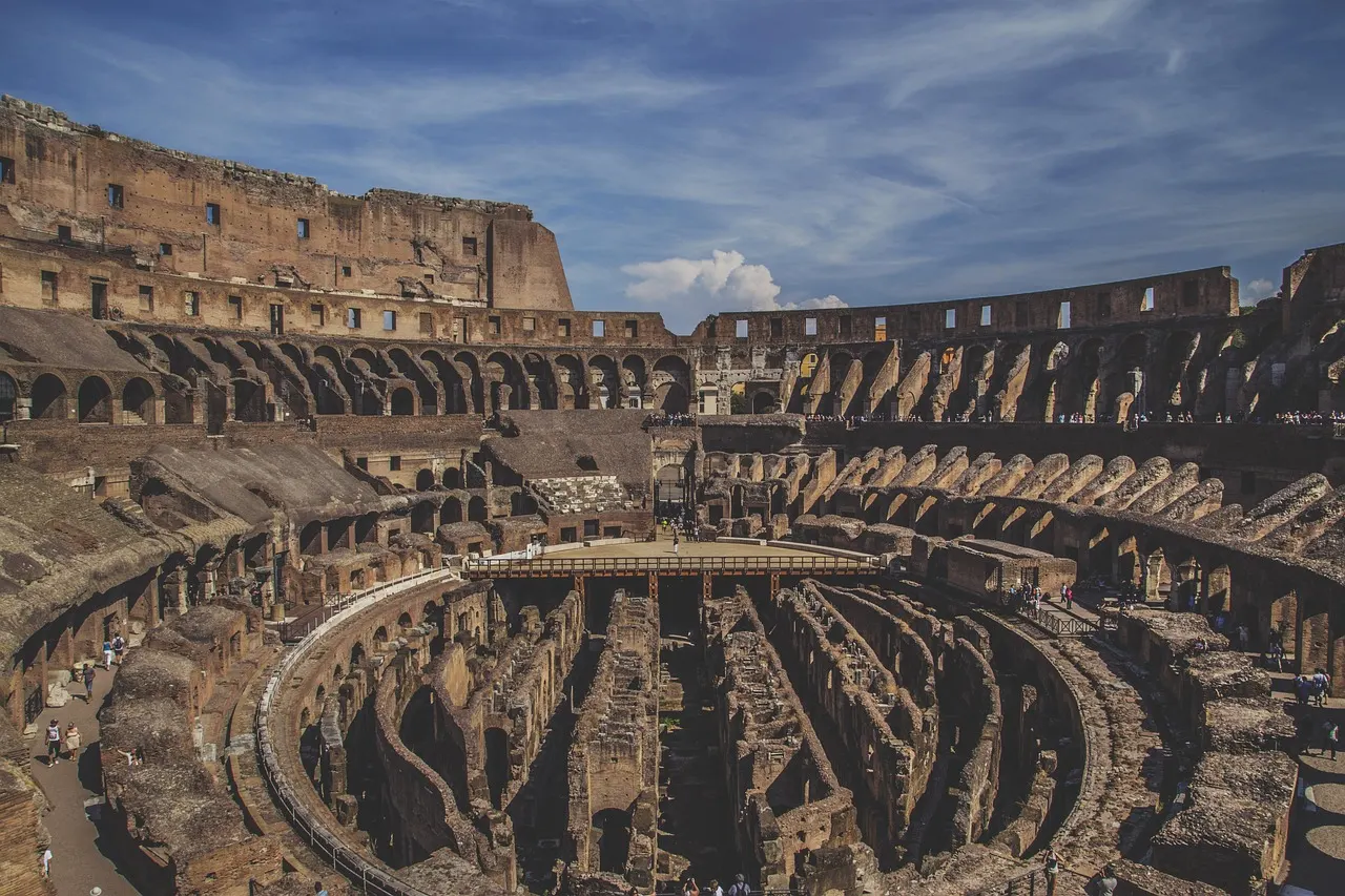 Interieur van het Colosseum met de blootgelegde ondergrondse gangen en de arena onder een blauwe lucht