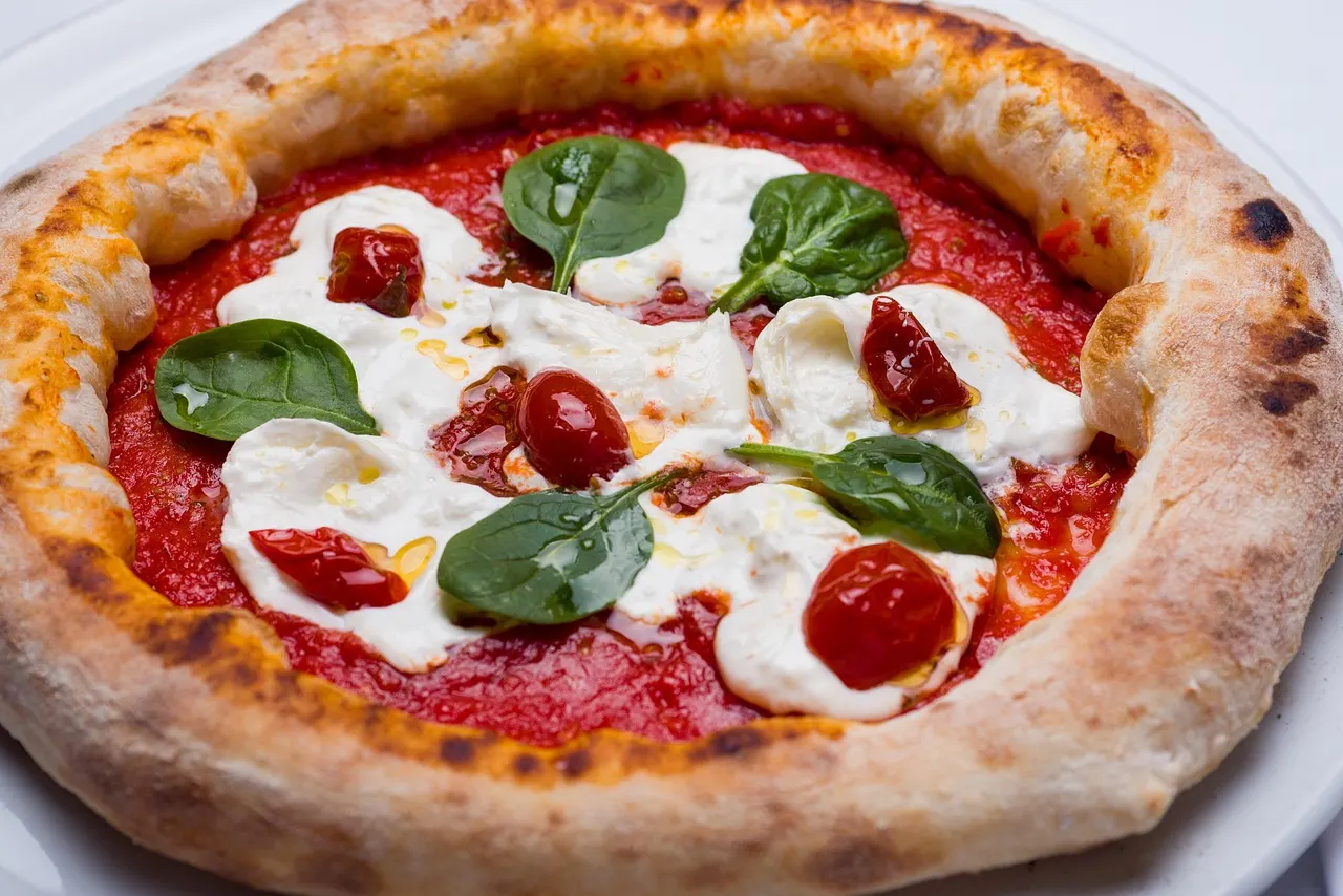 Napolitaanse pizza met tomatensaus, mozzarella, kerstomaatjes en verse spinazieblaadjes