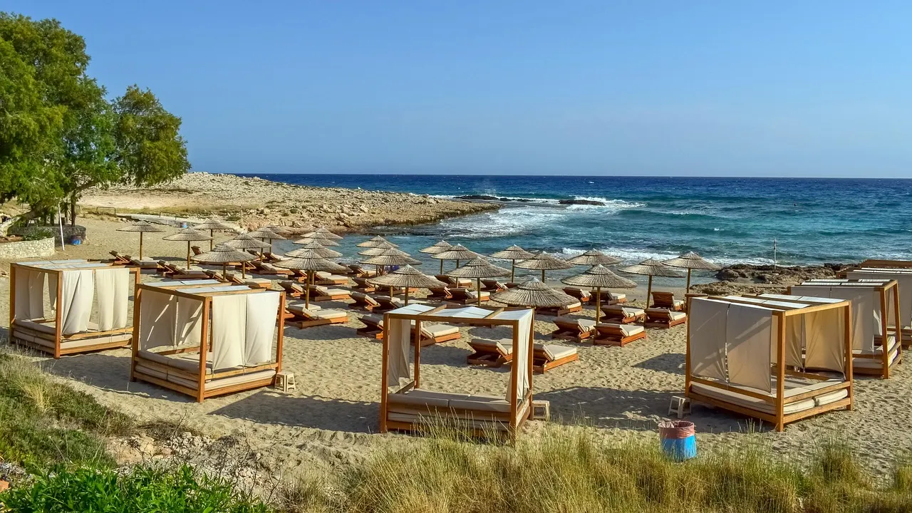 Zandstrand met strandbedden, parasols en ligpaviljoens aan een blauwe zee bij Ayia Napa